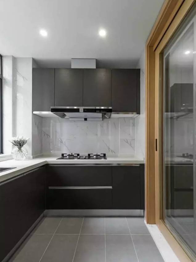 厨房黑白灰三色基调,地面铺设灰色水泥砖,极简的黑色橱柜.