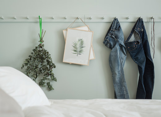 牛仔裤、干草和艺术品挂在构架上，颜色与卧室墙壁相同，呈浅绿色