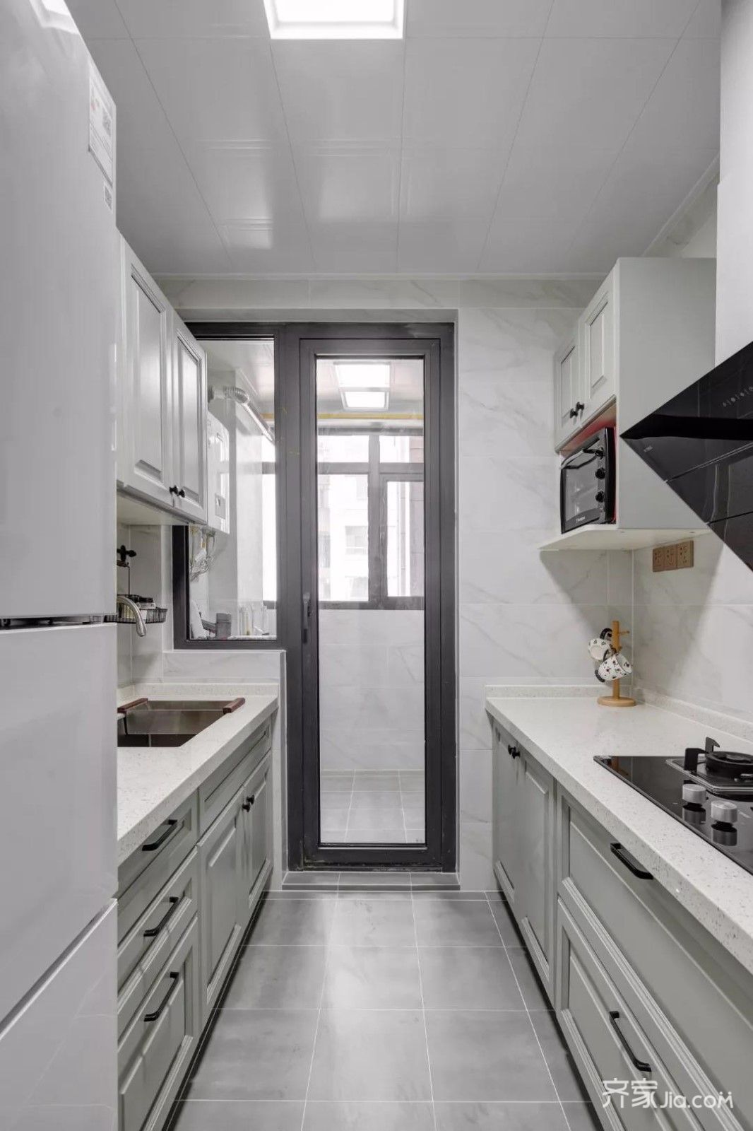 厨房地面铺设灰色哑光砖,墙面铺设大理石纹瓷砖,搭配上灰白色的橱柜