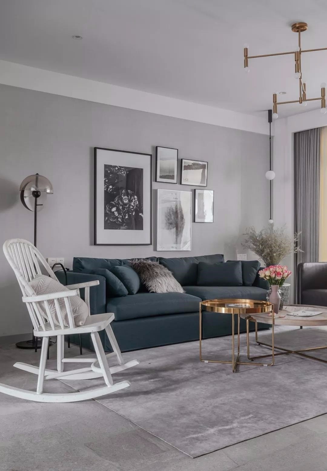 深蓝色布艺沙发搭配深灰色皮质单椅,木质铁件圆形茶几散发精致复古的